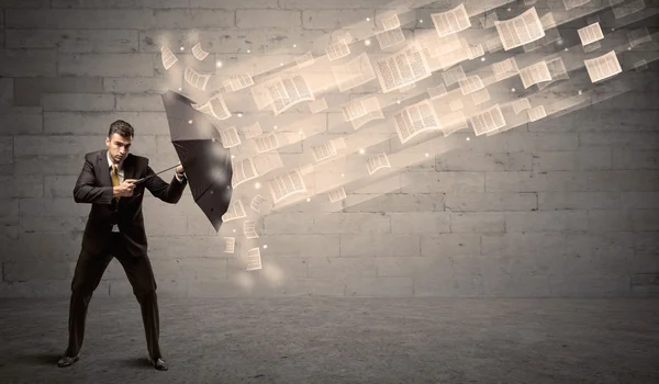 Деловой человек, защищающийся зонтиком от ветра бумаг — стоковое фото