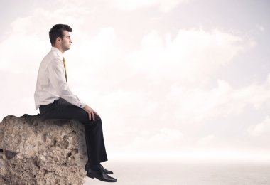 İş adamı taşın üstünde oturuyor.