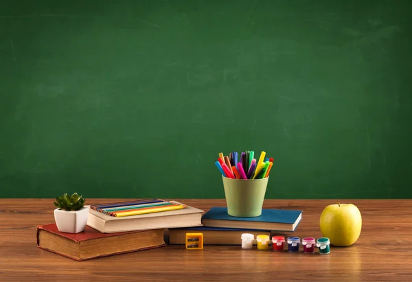 Schoolspullen op bureau met leeg schoolbord — Stockfoto