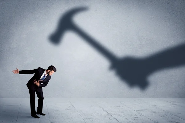 Business person afraid of a shadow hand holding hammer concept — Stock Photo, Image