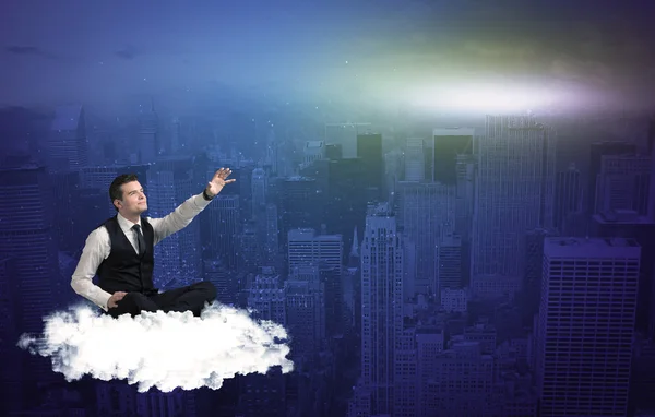 Hombre sentado en una nube sobre la ciudad — Foto de Stock