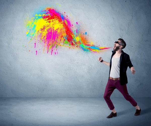 Hipster guy shouting colorful paint on wall — Stock Photo, Image