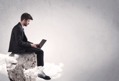 Ofis çalışanı kayanın tepesinde oturuyor.