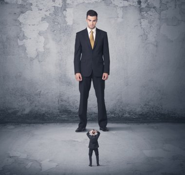 Büyük işletme zorbası küçük iş arkadaşına bakıyor.