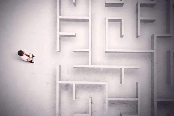 Запутавшийся бизнесмен стоит у лабиринтной стены — стоковое фото
