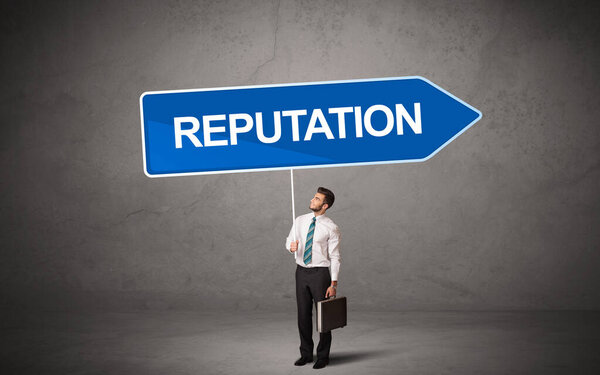 Молодой бизнесмен в случайном держании дорожного знака