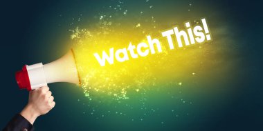 Genç bir kadın hoparlöre bağırıyor.