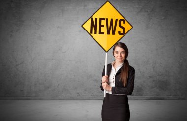 Genç iş adamı yol tabelasını tutuyor.