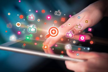 Sosyal medya simgelerine sahip tablet kullanan bir elin yakın plan görüntüsü