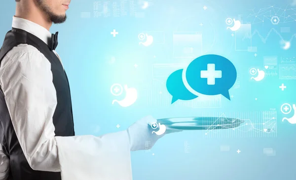 Handsome young waiter in tuxedo holding healthcare icons on tray — Stock Photo, Image