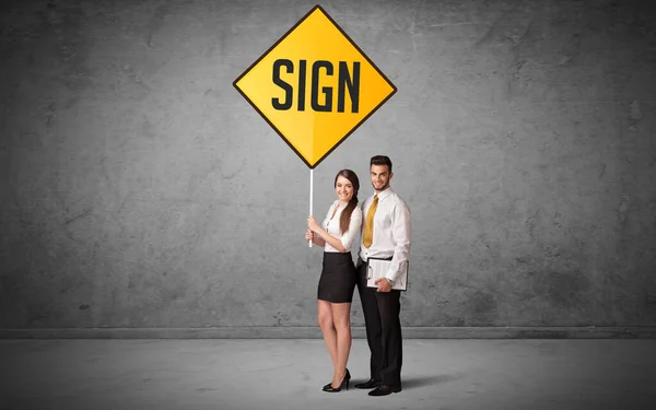 Young business person holding road sign — Stock Photo, Image