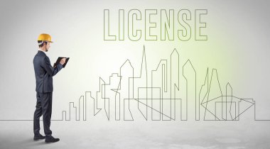 Kasketli bir iş adamı elinde planlar tutuyor