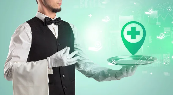 Handsome young waiter in tuxedo holding healthcare icons on tray — Stock Photo, Image