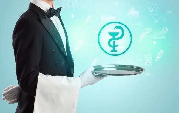 Красивый молодой официант в смокинге держит иконы здравоохранения на подносе — стоковое фото