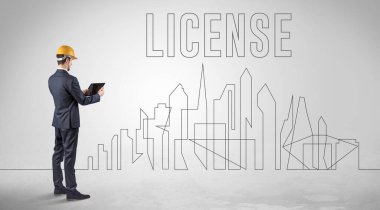 Kasketli bir iş adamı elinde planlar tutuyor