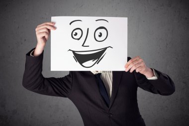 empresario sosteniendo una cartulina con cara sonriente en él en frente 
