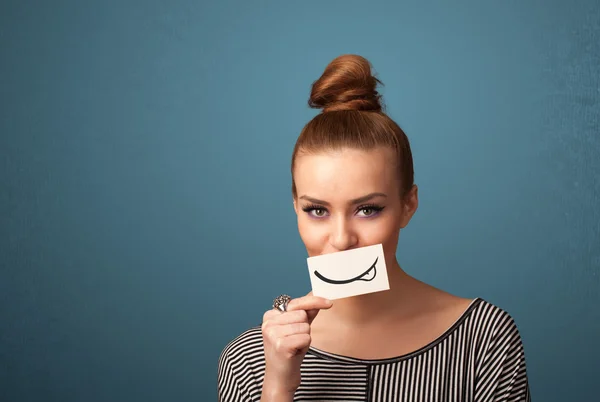 Chica bastante joven sosteniendo la tarjeta blanca con dibujo sonrisa — Foto de Stock