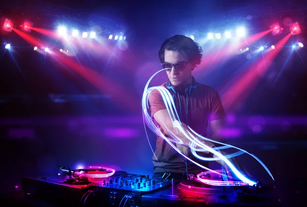 Discjockey som spelar musik med ljusstrålen effekter på scenen — Stockfoto