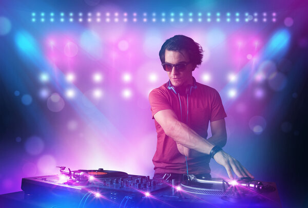 Disc jockey mixing music on turntables on stage with lights and 