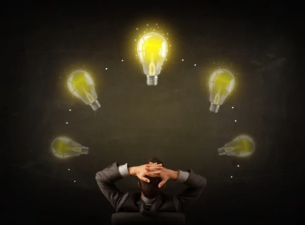 Businessman sitting with lightbulbs over his head — Stock Photo, Image