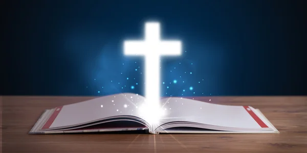 Open holy bible with glowing cross in the middle — Stock Photo, Image