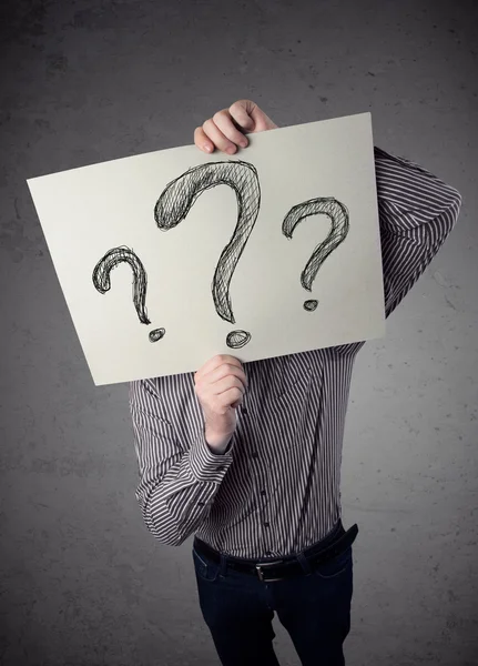 Businessman holding a paper with question marks in front of his — Stock Photo, Image