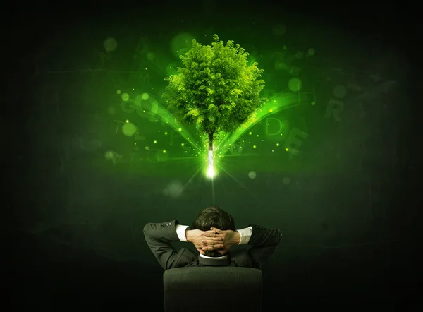 Podnikatel v křesle sedí před zářícím stromem — Stock fotografie