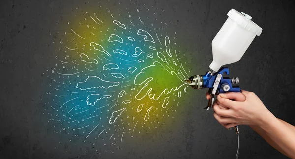 Worker with airbrush gun paints colorful lines and splashes — Stock Photo, Image