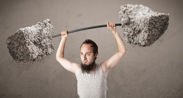 Skinny guy lifting large rock stone weights — Stock Photo, Image