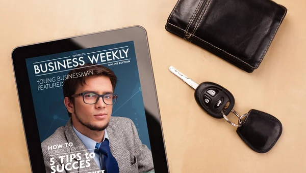 Tablet pc showing magazine on screen with a cup of coffee on a d