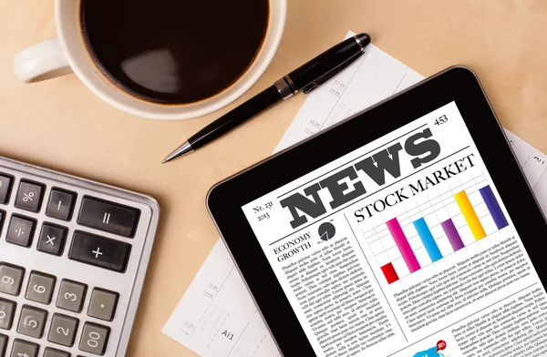 Tablet pc toont nieuws op het scherm met een kopje koffie op een bureau — Stockfoto