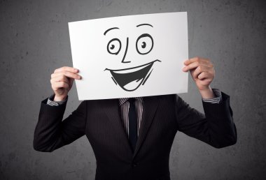 empresario sosteniendo una cartulina con cara sonriente en él en frente 