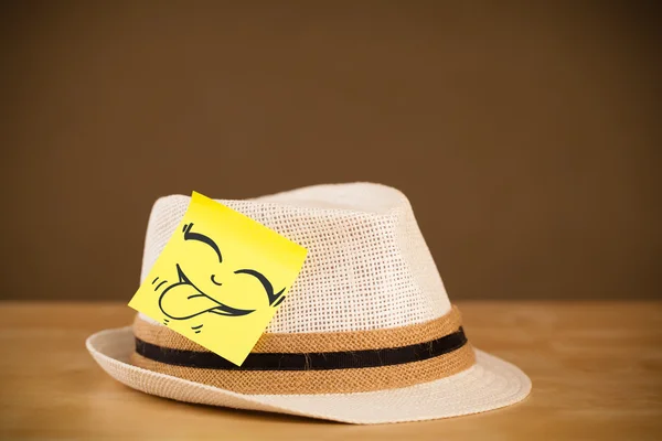 Nota post-it con la cara sonriente pegada en un sombrero — Foto de Stock