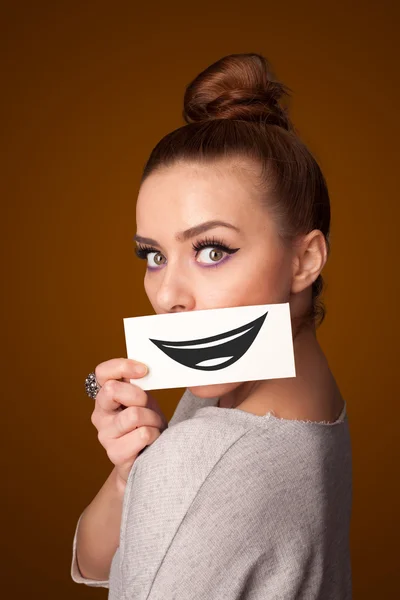 Feliz bonita mujer sosteniendo tarjeta con divertido smiley — Foto de Stock