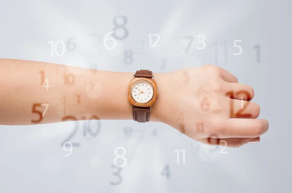 Mão com relógio e números no lado que sai — Fotografia de Stock