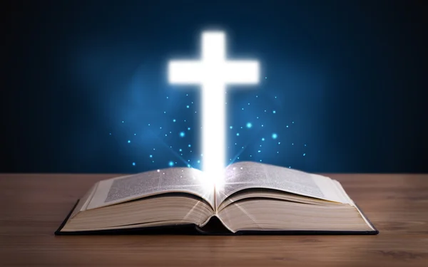 Abra a Bíblia sagrada com cruz brilhante no meio — Fotografia de Stock