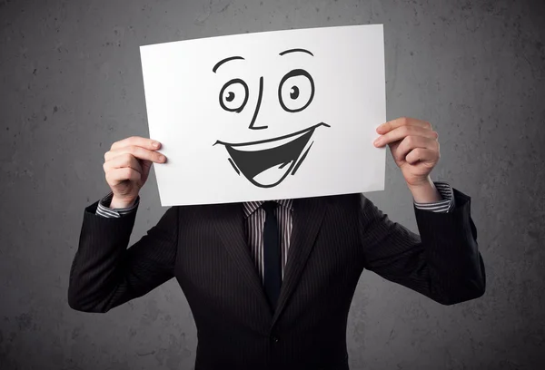 Businessman holding a cardboard with smiley face on it in front — Stock Photo, Image