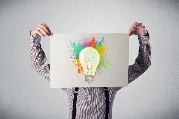 Empresário segurando um papelão com salpicos de tinta e lightbul — Fotografia de Stock