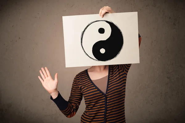 Woman holding a paper with a yin-yang on it in front of her head — Stock Photo, Image