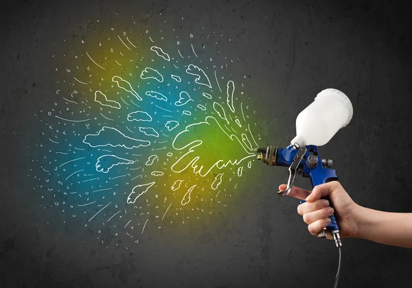 Worker with airbrush gun paints colorful lines and splashes — Stock Photo, Image