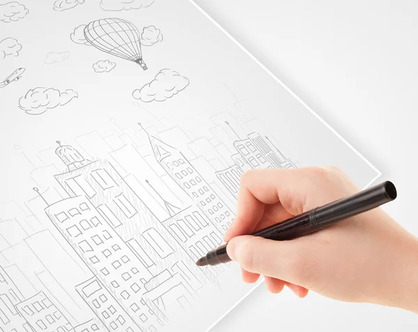 A person drawing sketch of a city with balloons and clouds on a — Stock Photo, Image