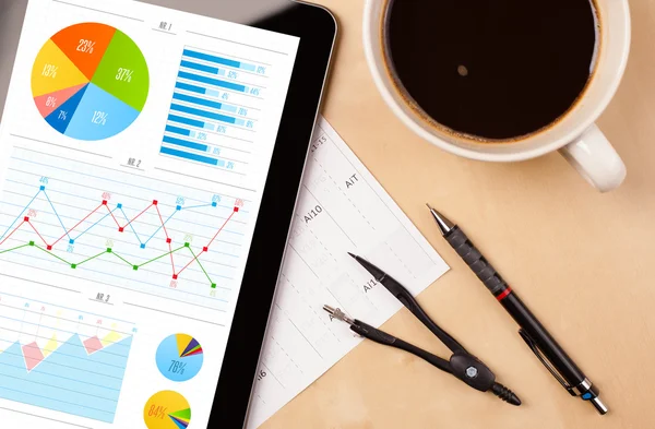 Tablet pc shows charts on screen with a cup of coffee on a desk — Stock Photo, Image