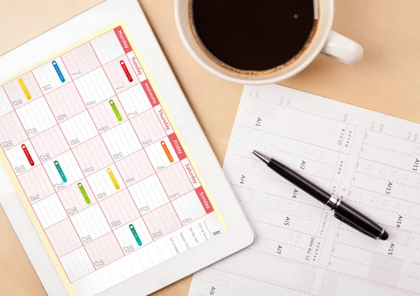 Tablet pc showing calendar on screen with a cup of coffee on a d — Stock Photo, Image