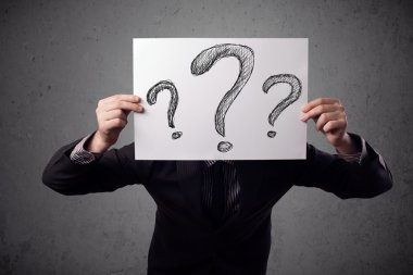 onun önünde soru işareti olan bir kağıt tutan işadamı 