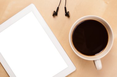 Boş alanı olan bir tablet bilgisayar ve masada bir fincan kahve.