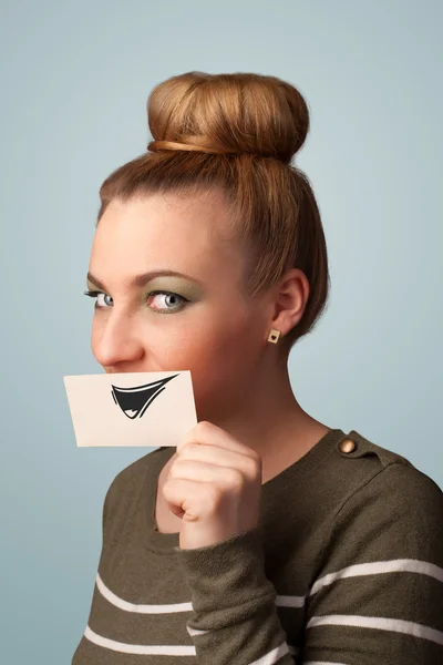 Happy cute girl holding paper with funny smiley drawing — Stock Photo, Image