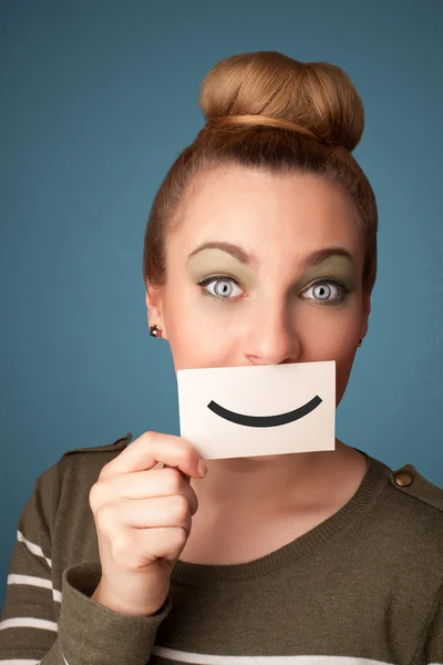 Happy pretty woman holding card with funny smiley — Stock Photo, Image