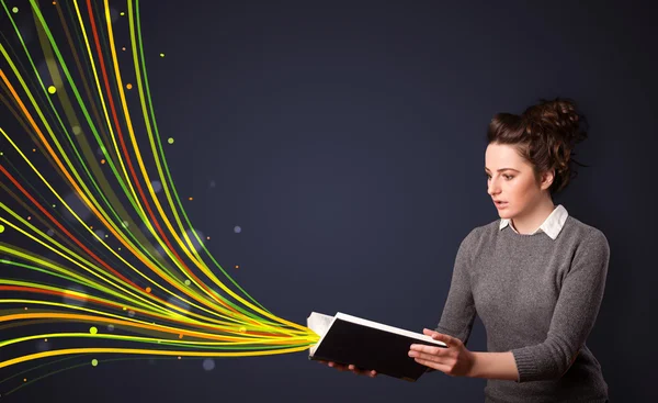 Pretty young woman reading a book while colorful lines are comin — Stock Photo, Image