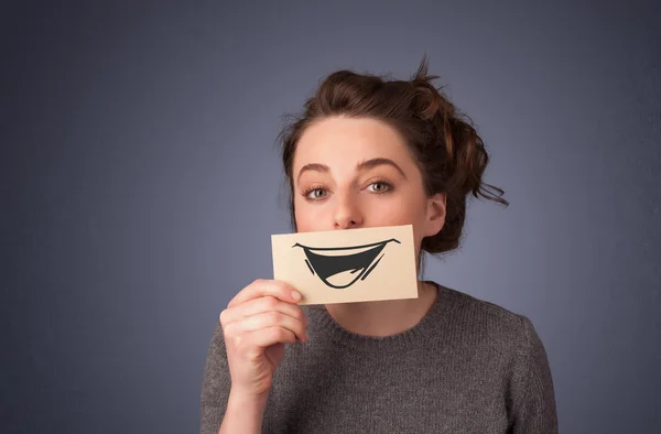 Felice ragazza carina in possesso di carta con divertente disegno smiley — Foto Stock