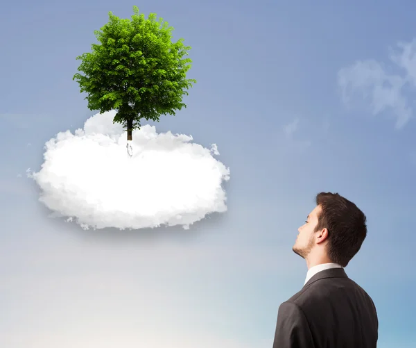 Jovem apontando para uma árvore verde em cima de uma nuvem branca — Fotografia de Stock